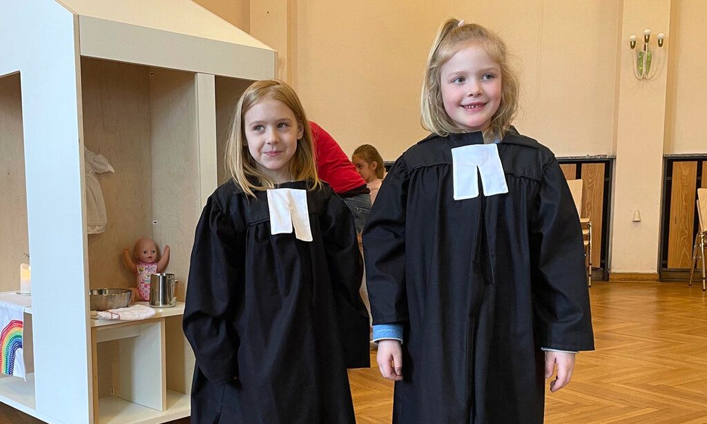 Zwei Mädchen mit Talaren in der Spielkirche