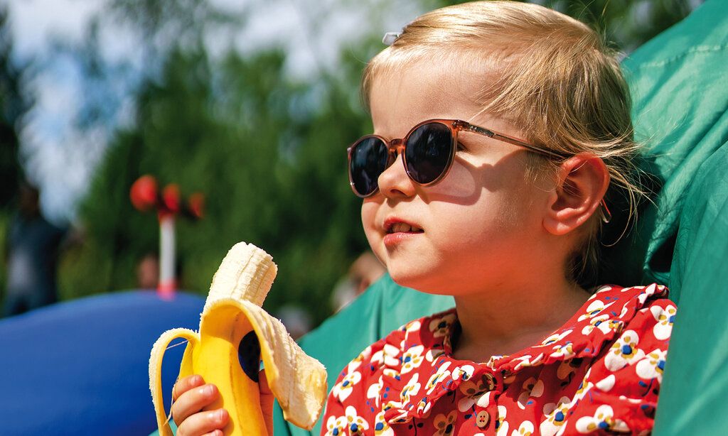 Porträt eines Mädchens mit Sonnenbrille und Banane
