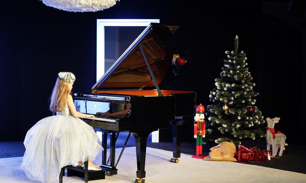Mädchen spielt Klavier, die Bühne ist weihnachtlich dekoriert