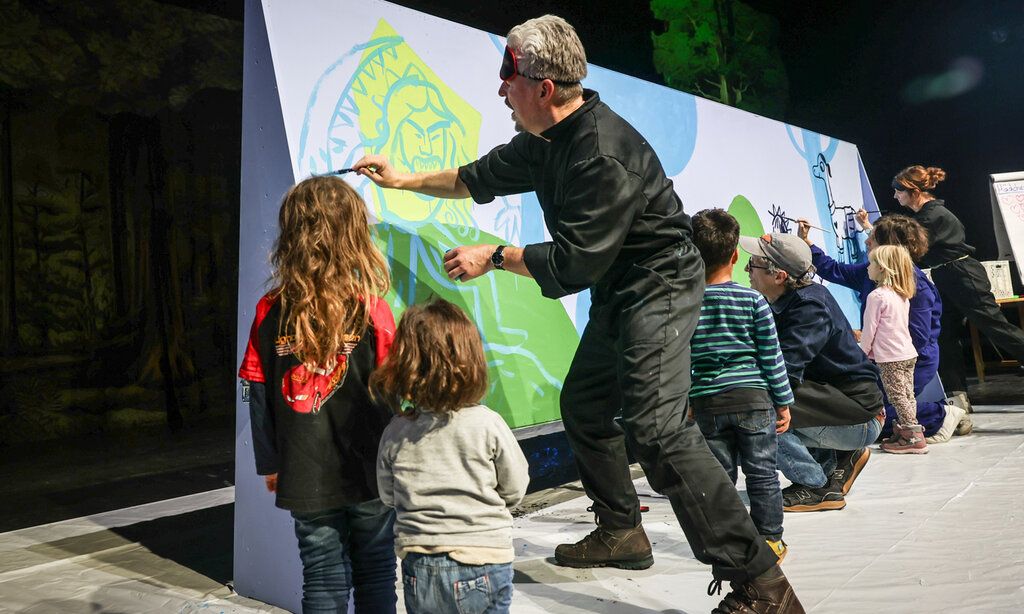 Martin Baltscheit malt auf eine große Papierplane, andere Erwachsene und Kinder malen mit oder gucken zu