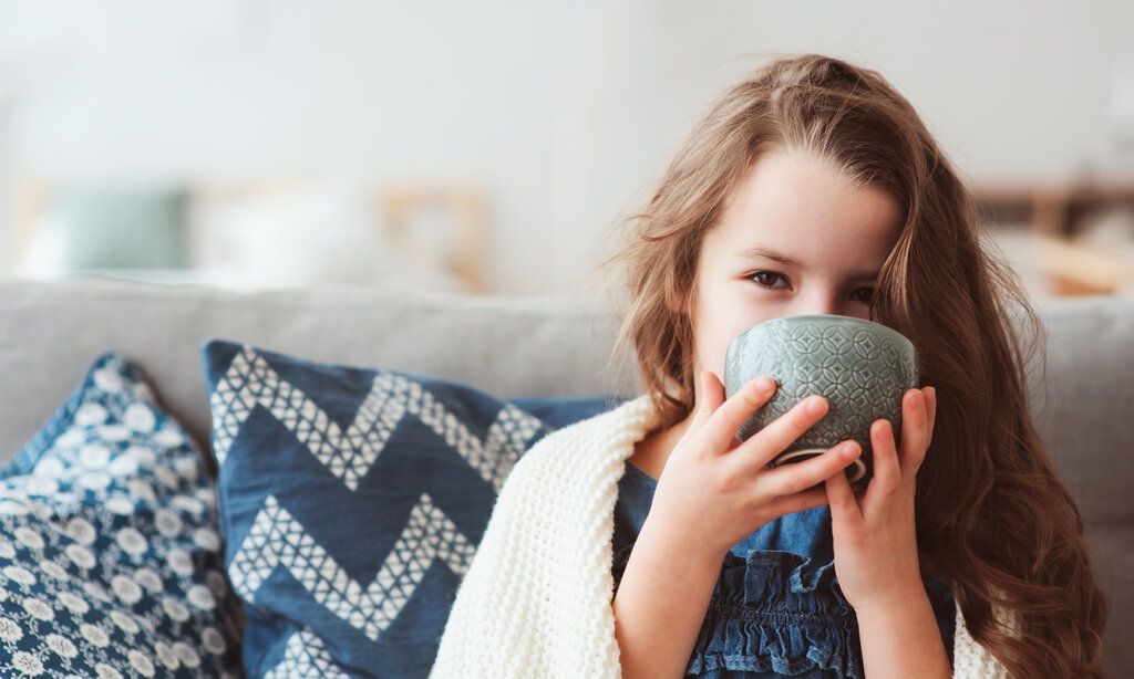 Kind auf dem Sofa trinkt aus einer Schale