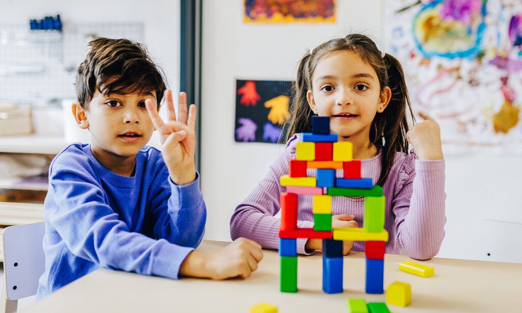 ein Junge und ein Mädchen sitzen am Tisch und haben Bauklötze gestapelt
