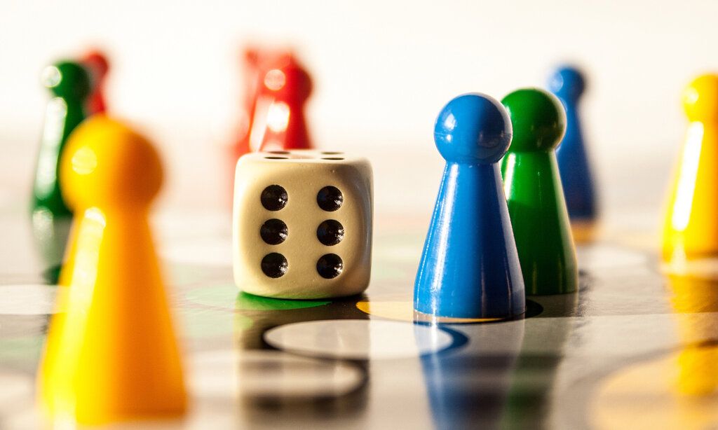 Mensch-ärgere-dich-nicht-Figuren und ein Würfel auf einem Spielbrett