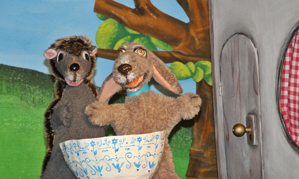 Igel- und Hund-Handpuppen mit einer Schale auf Puppenbühne