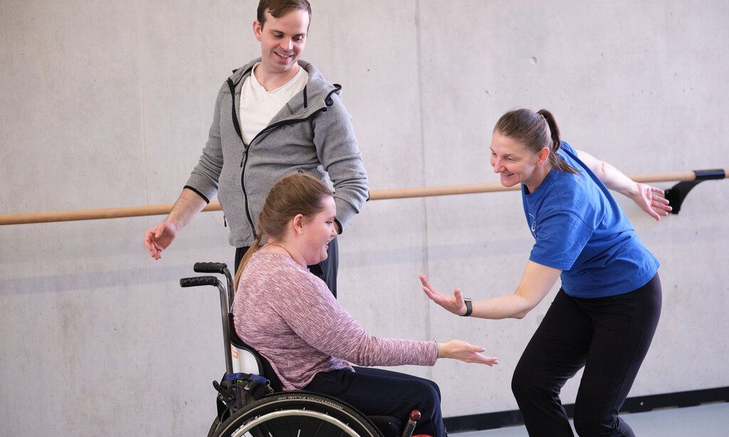 Drei Personen tanzen, eine sitzt dabei im Rollstuhl