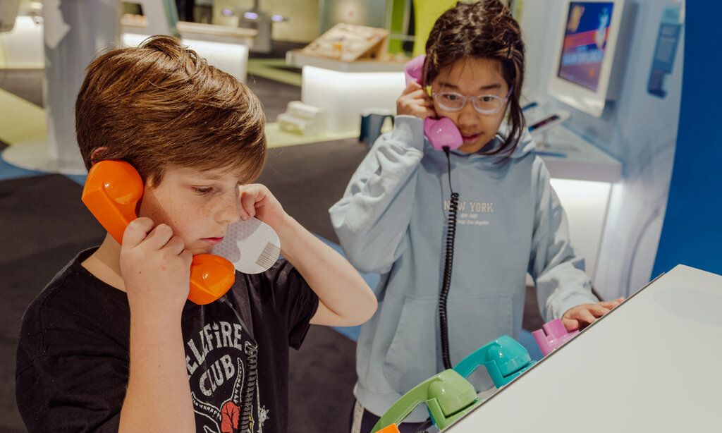 Zwei Kinder telefonieren mit bunten Telefonen auf der MS Wissenschaft