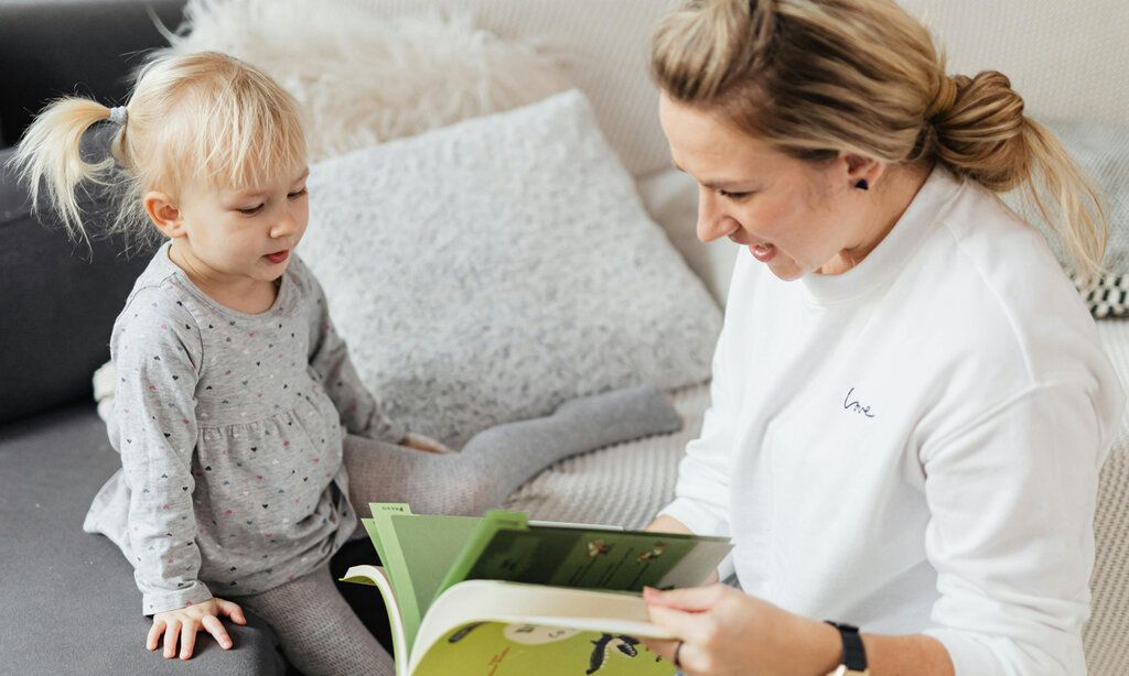 Mutter liest Tochter aus Buch vor