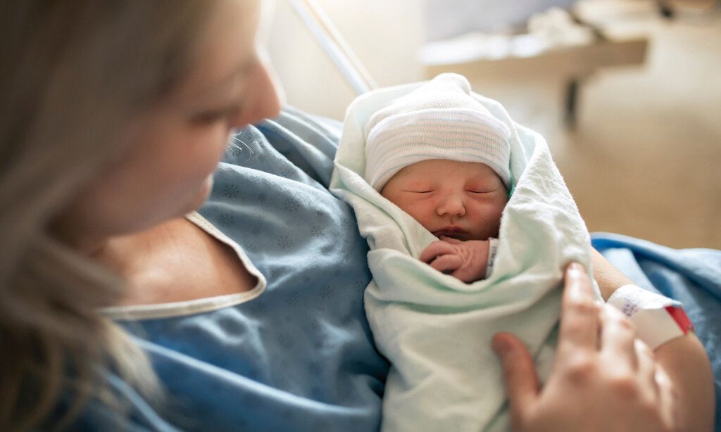 Junge Mutter hält ihr neugeborenes Baby im Arm