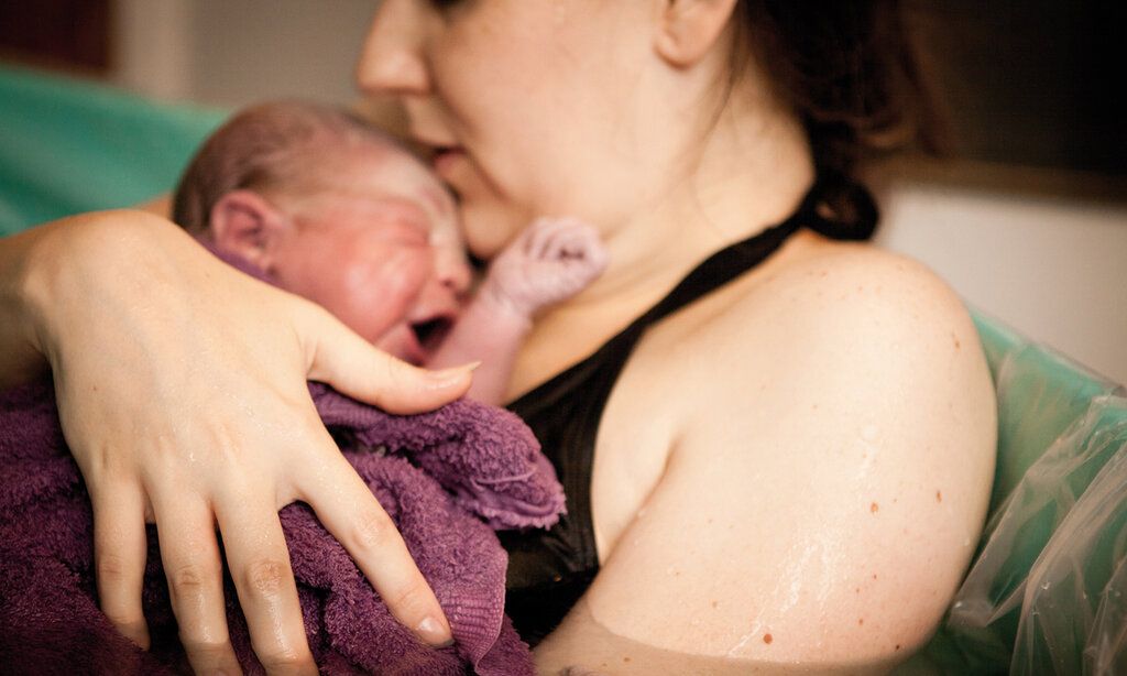 Mutter liegt mit neugeborenem Baby in einer Geburtswanne