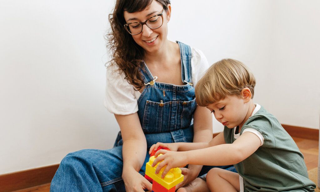 Mutter und Kind spielen mit bunten Bauklötzen