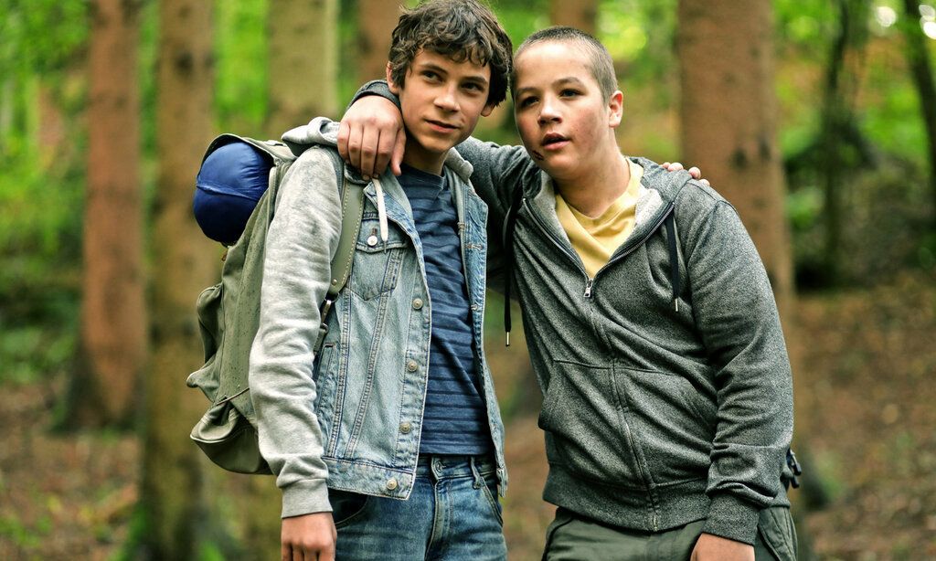 Zwei Jungs stehen Arm in Arm im Wald und wirken erschöpft