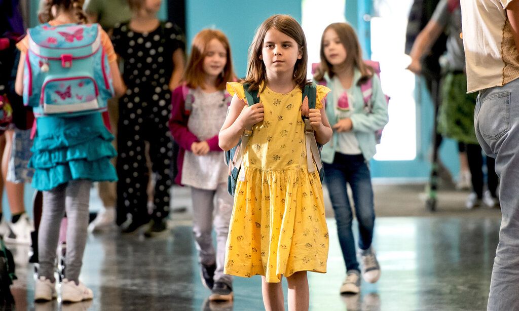 Junge geht mit einem gelben Kleid über einen Schulflur