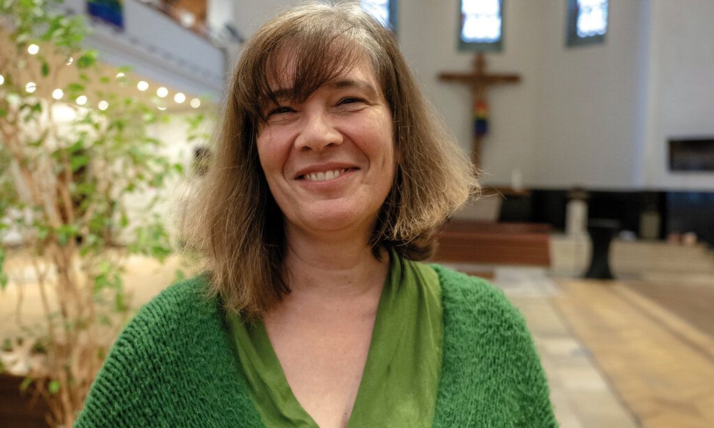 Nicole Mechtenberg steht in einer Kirche und lacht in die Kamera