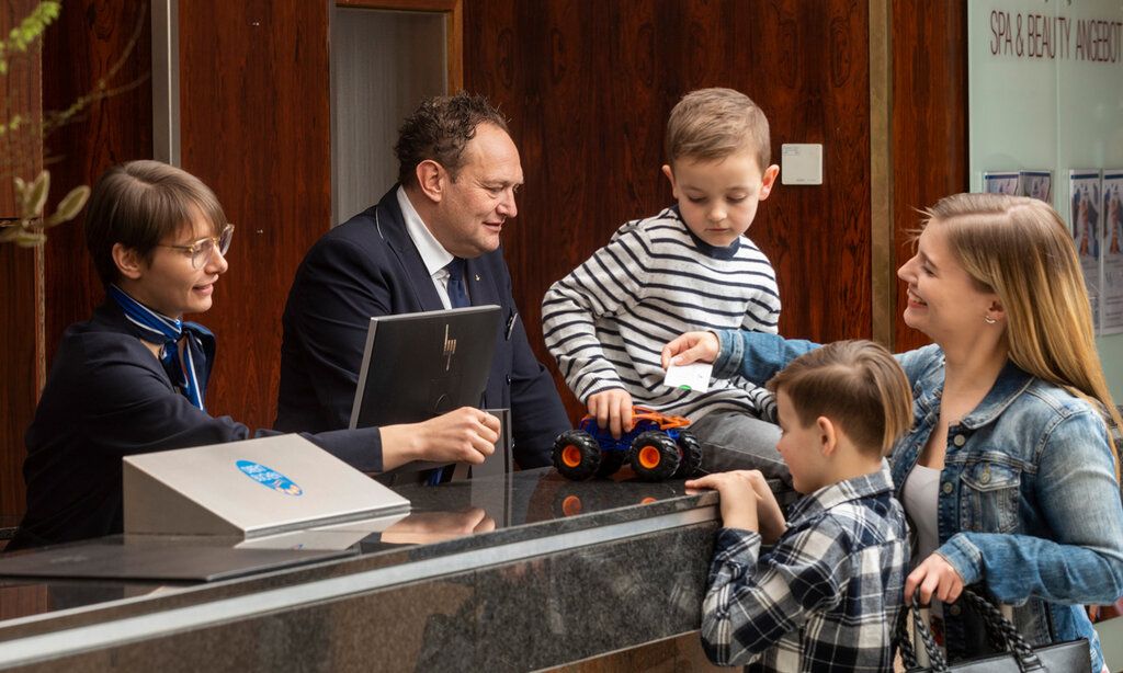 Mutter mit zwei Kindern an der Rezeption im Maritim Travemünde