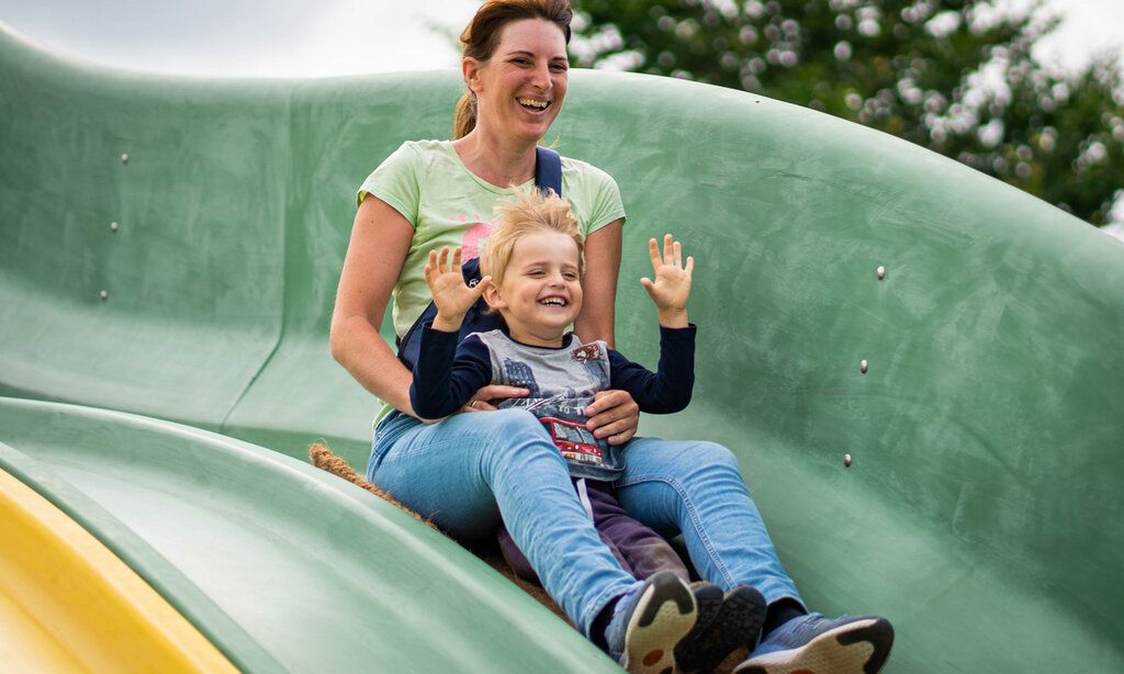 Mutter und Sohn rutschen lachend auf einer Rutsche im Bubenheimer Spieleland