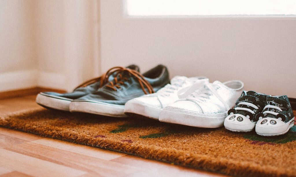 drei Paar Schuhe vor der Wohnungstür, von Vater, Mutter und Kleinkind