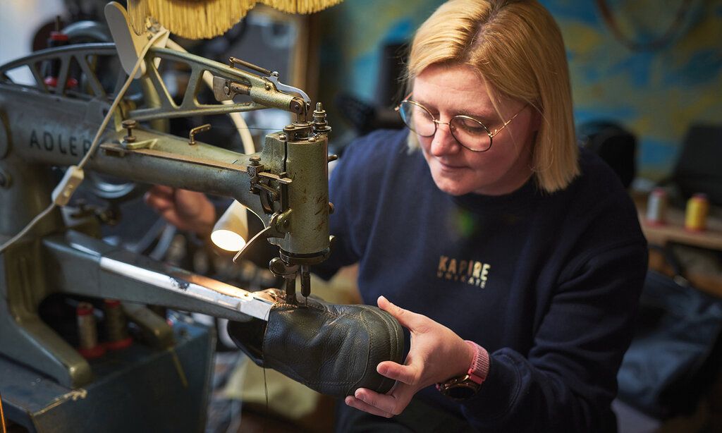 Schusterin bearbeitet einen Schuh an einer Maschine