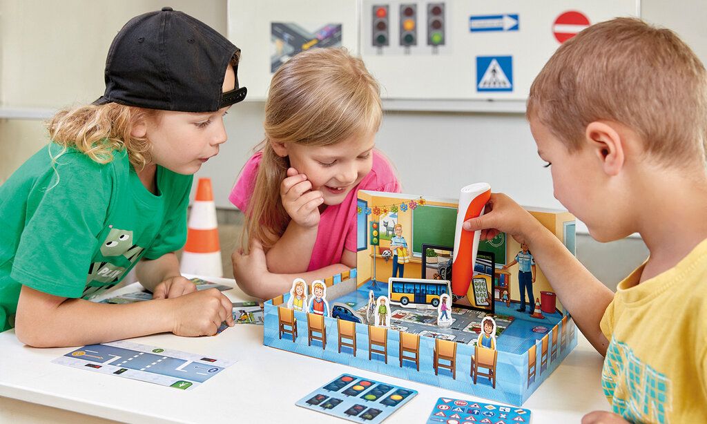 Drei Kinder spielen das Tiptoi-Spiel „Sicher durch den Straßenverkehr“