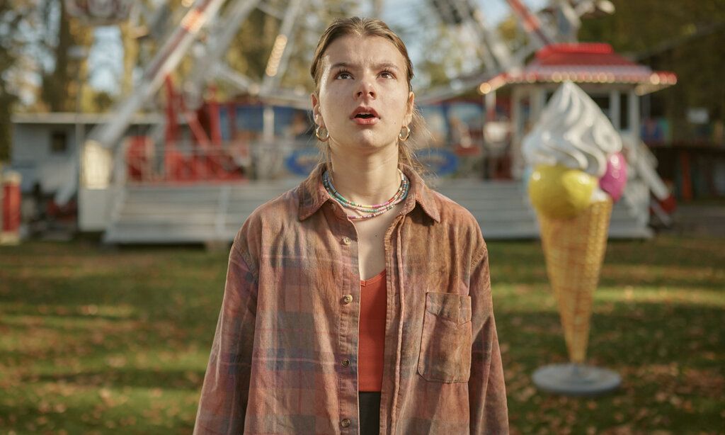 Mädchen steht auf einem Kirmesplatz und guckt stauenend nach oben