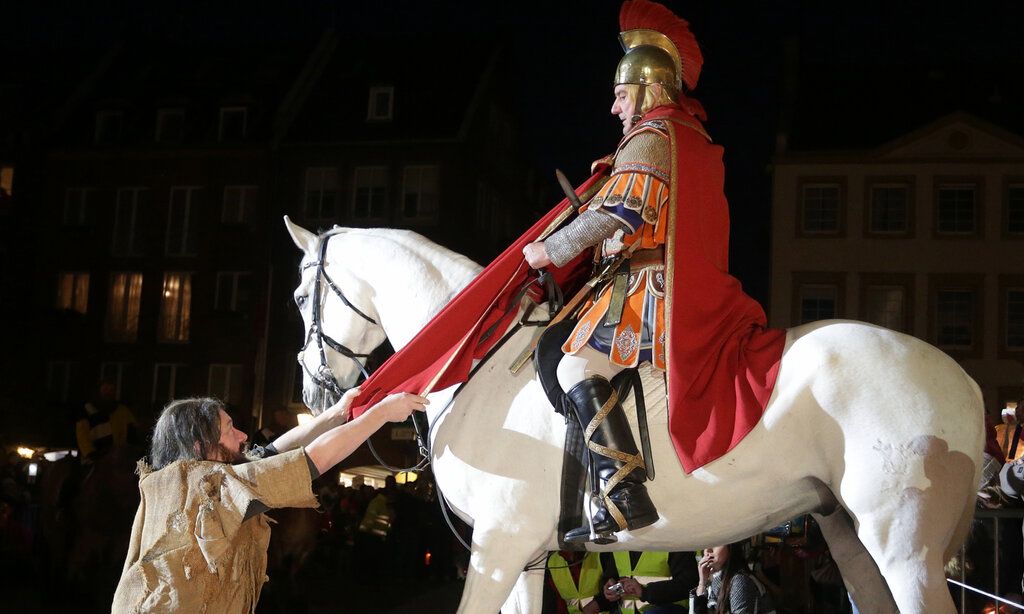 St. Martin sitzt auf seinem Pferd, teilt den Mantel, gibt ihn dem Bettler, abends vor dem Düsseldorfer Rathaus