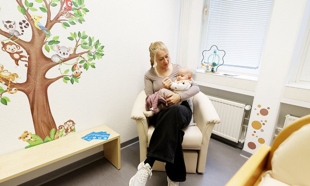 eine Frau sitzt mit ihrem Baby im Still- und Wickelraum am Hbf