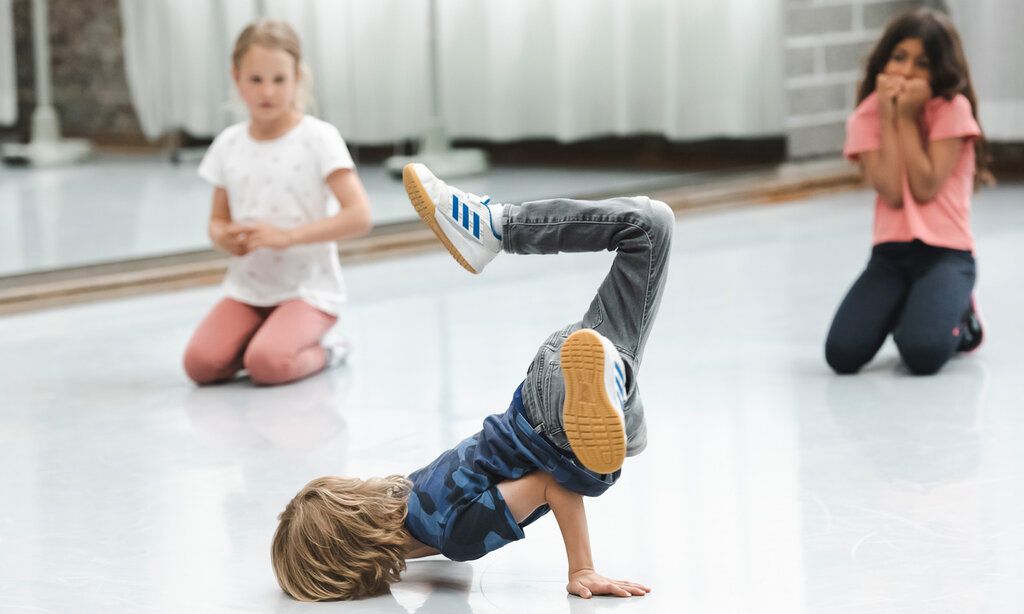 Junge macht Breakdance im Tanzhaus NRW, zwei Mädchen gucken zu