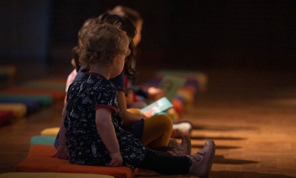 Kleine Mädchen sitzen in der Tonhalle auf Sitzkissen und lauschen einem Konzert