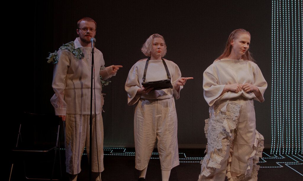 zwei Schauspielerinnen und ein Schauspielet stehen auf einer dunklen Bühne