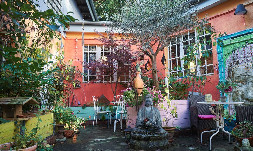Bunter Innenhof mit Budddha-Figur, Tischen, Stühlen und Pflanzen