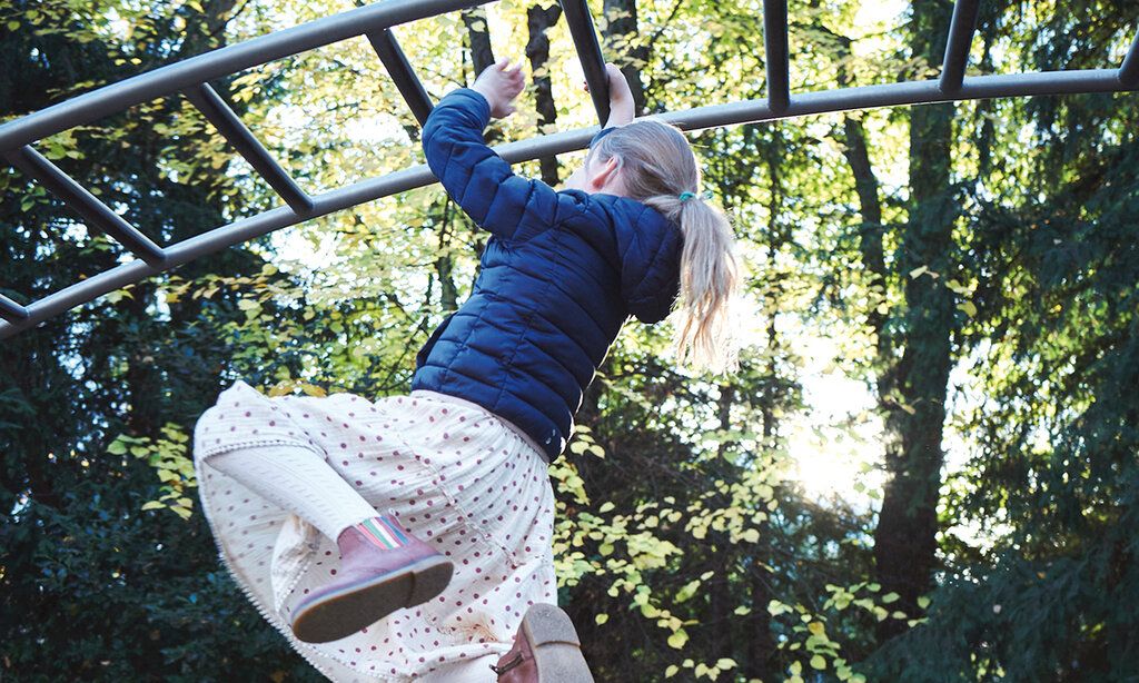 Mädchen hangelt an einem Klettergerüst