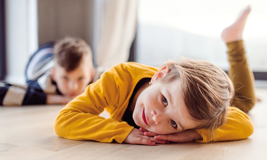 Zwei Kinder liegen auf dem Fußboden herum und machen nichts
