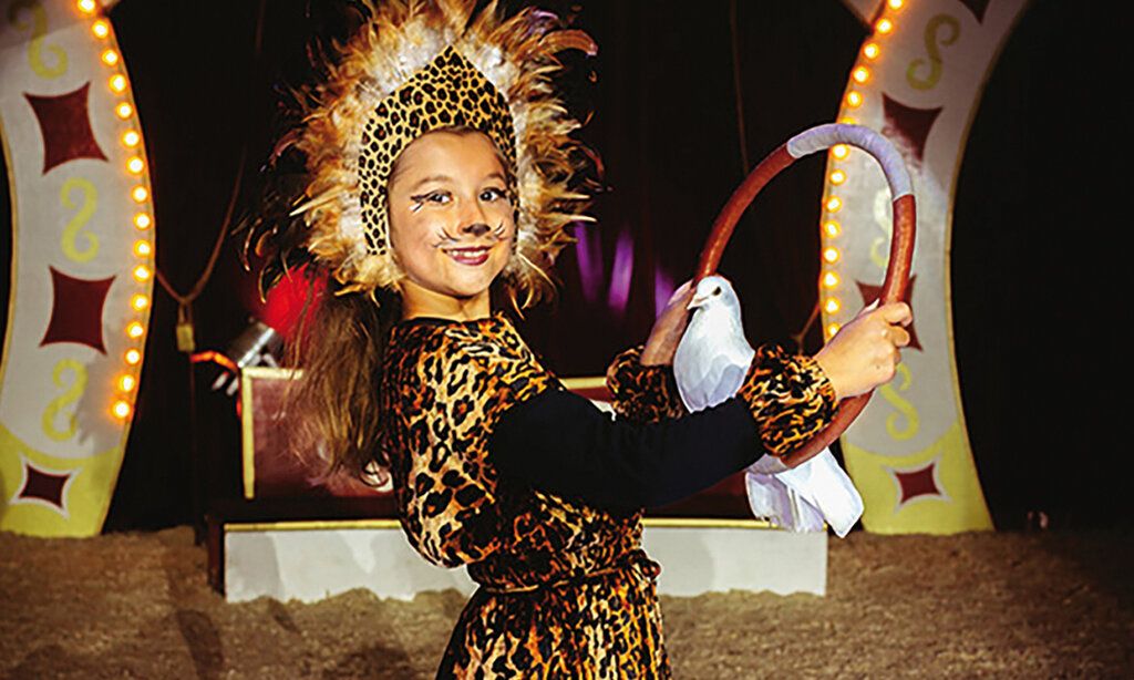 Verkleidestes Mädchen mit einer weißen Taube im Winterzirkus