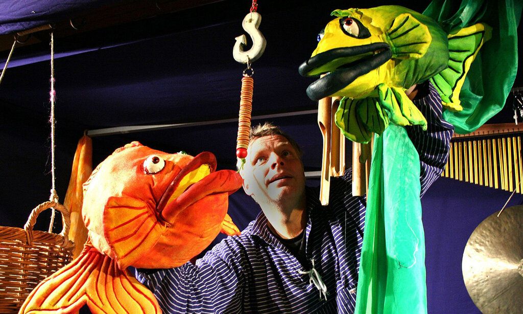 Puppenspieler mit zwei Fisch-Handpuppen in orange und grün