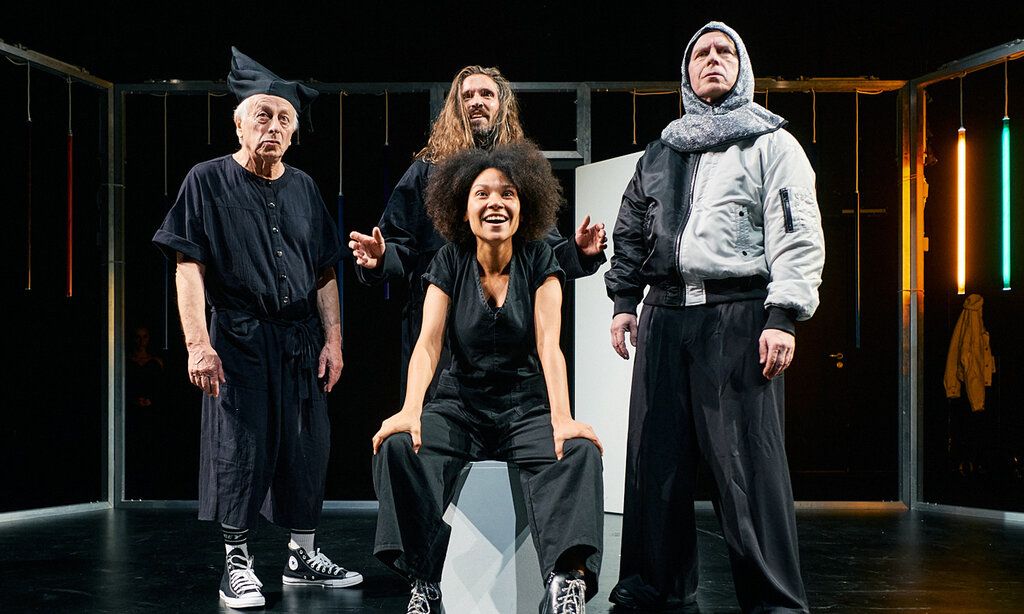 drei Schauspieler und eine Schauspielerin stehen auf einer dunklen Bühne