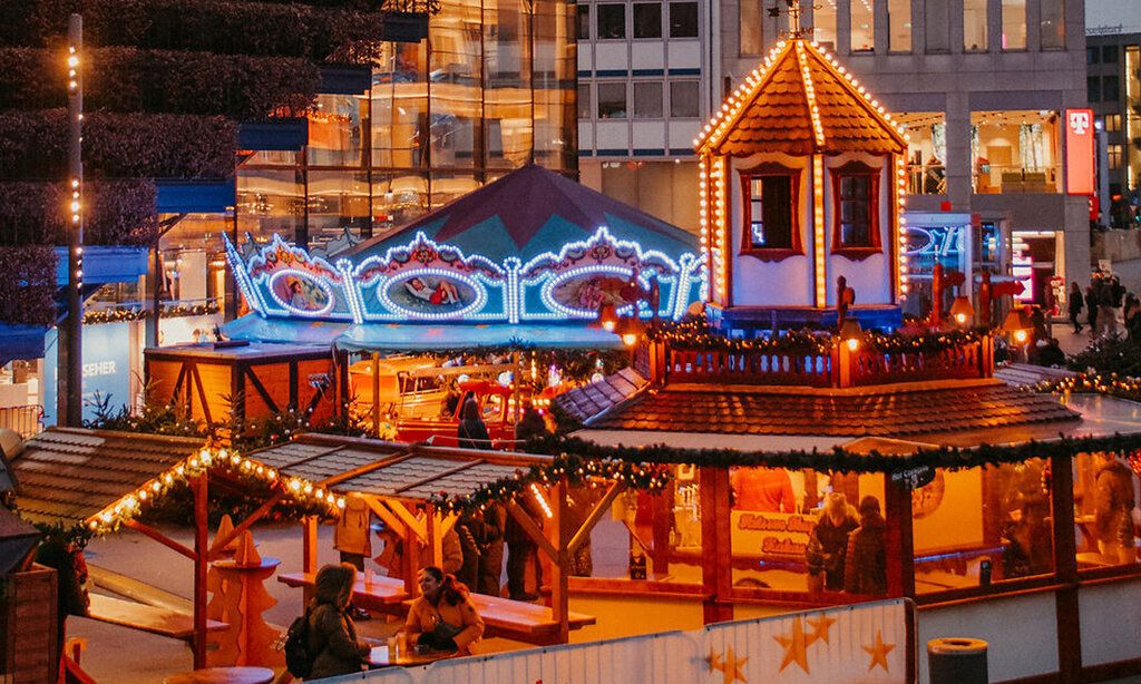 Beleuchtete Weihnachtsmarktstände am Köbogen in der Dämmerung