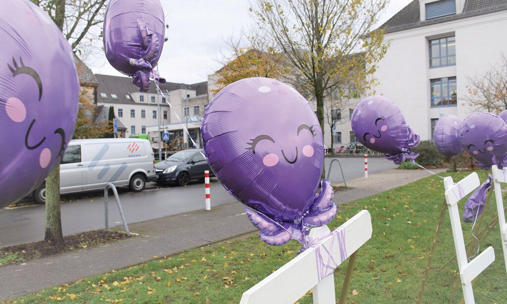 Violette Luftballons, die wie Kraken aussehen vor Klinikgebäude