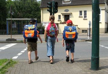 Drei Schulanfänger am Straßenüberweg