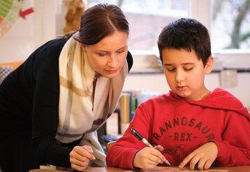 Betreuerin hilft Schüler bei den Hausaufgaben