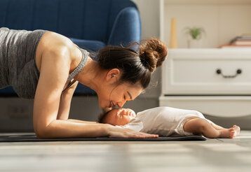 Mutter Yoga-Planke mit neugeborenem Jungen schlafen und auf Yogamatte liegen