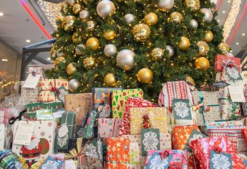 Viele bunte eingepackte Weihnachtsgeschenke liegen unter einem geschmückten Weihnachtsbaum