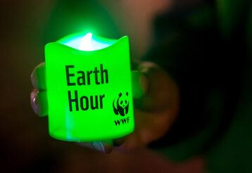 Eine grüne LED-Kerze mit der Beschriftung: Earth Hour und dem WWF-Logo, leuchtet im Dunklen