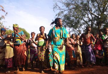 Junge afrikanische Frauen tanzen bunt gekleidet draußen