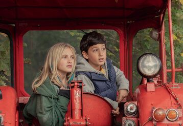 Ein Mädchen und ein Junge auf einem roten Traktor
