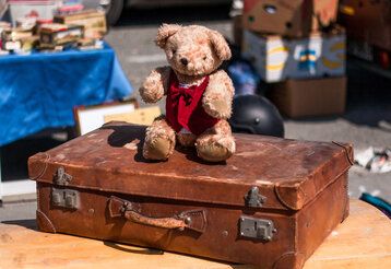 Ein alter Teddybäar sitzt auf einem alten Lederkoffer