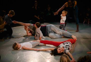 Drei Tänzer:innen tanzen mit kleinen Kindern auf dem Bühnenboden.