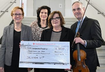 Dr. Doris Bischler (l.), Leiterin Clara-Schumann-Musikschule, und Michael Bremen, Vorsitzender des Fördervereins, erhielten eine Spende in Höhe von 25.000 Euro und eine Violine vom Vorstand der Stiftung, Anette Fischer (2.v.l.) und Angelika Voller