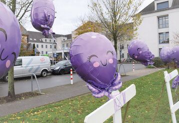 Violette Luftballons, die wie Kraken aussehen vor Klinikgebäude