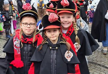 Drei Mädchen in Kostümen der Düsseldorfer Bürgerwehr beim Rosenmontagszug