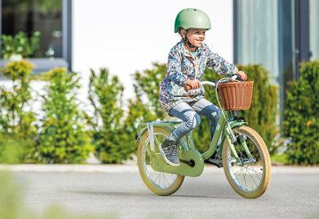 ein Mädchen mit Helm fährt auf einem Puky-Fahrrad