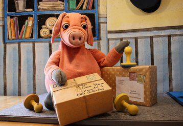 Das Schweinchen Rosa-Luise inmitten von Päckchen auf einem Postamt